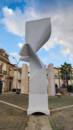 Modern geometrical sculpture located in the middle of a square. Front wide view Artwork by Dado