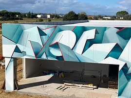 Closer front view of a graffiti paint work on the external walls of a big building representing flat ribbons bent in geometrical shapes, light blue and white shades with thin red outlines. Artwork by Dado