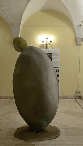 A big stone in the middle of the art gallery, with another smaller stone on top which is positioned in an impossible balance close to fall down the floor. Sculpture by Dado
