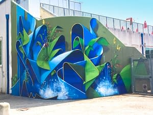 Total view of a large mural painting depicting wide sinuous blue ribbons decorated with purple, red and yellow flowers and green leaves and water splashes. Artwork by Dado