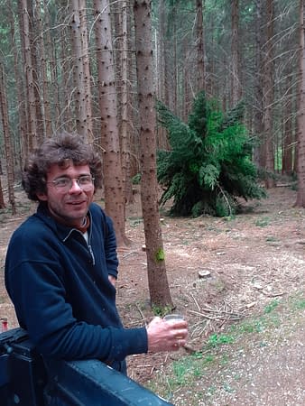 The artist Dado in the forest with one of his organic dandelion installations in the background.