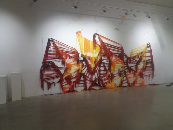 The skeleton of a wool made graffiti in the tones of yellow, orange and various reds inside a gallery, after being ripped. Artworks by Dado