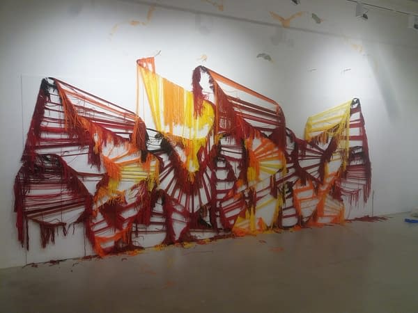 The skeleton of a wool made graffiti in the tones of yellow, orange and various reds inside a gallery, after being ripped.Closer view. Artworks by Dado