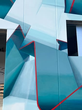 Close-up detail of a graffiti paint work on the external walls of a big building representing flat ribbons bent in geometrical shapes, light blue and white shades with thin red outlines. Artwork by Dado
