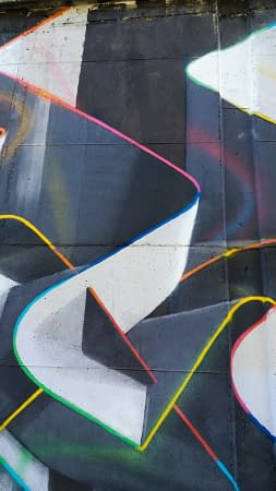 Mural painting representing weaving stiff ribbons forming the name of the artist Dado, in dark grays and white tones with sharp cutting multi color outline. Detail