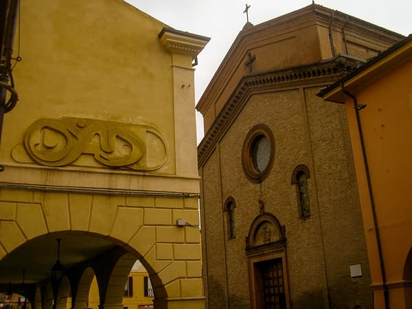 Bas-relief sculpture in a contemporary graffiti lettering fixed on a above a Medieval vault architecture. In the background an old Church. Artwork by Dado