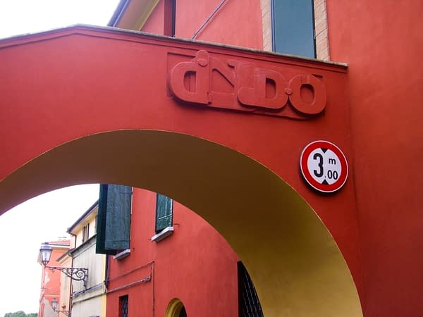 Bas-relief sculpture in a contemporary graffiti lettering fixed on a above a Medieval bridge red architecture. Front view Artwork by Dado