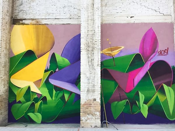 A triptych mural painting of flowers in three different colors on a white bricks wall in a wide open space, double flower view. Artwork by Dado