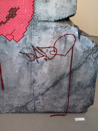 A closeup detail of Dado's tag stitched on a rock sculpture.