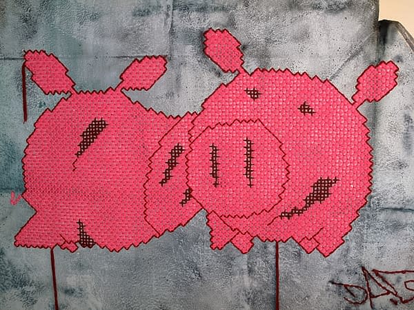 A closeup detail of two wool made flat pig characters stitched on a big rock sculpture. Artwork by Dado