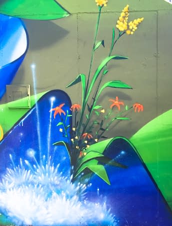 Detail of a mural painting depicting wide sinuous blue ribbons decorated with purple flowers and green leaves and water splashes. Artwork by Dado