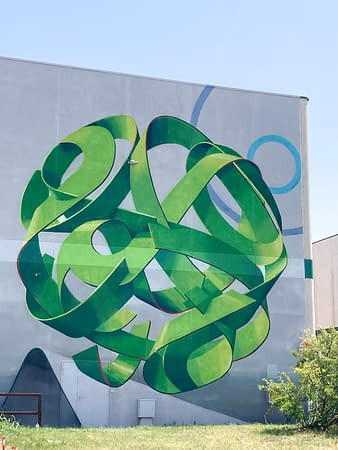Total view of a mural painting depicting a spherical wildstyle graffiti forming the tag Dado in green tones.
