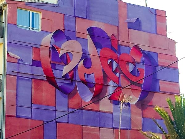 Bottom view of a Mural painting on an high building face depicting floating bent ribbons creating two names altogether the tag Dado and the name Eva in a pale red and electric blue tones