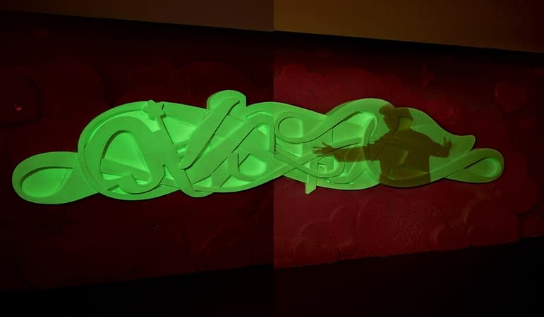 Bas-relief sculpture in a contemporary graffiti lettering luminescent green color covered by the shadow the. Front wide view Artwork by Dado