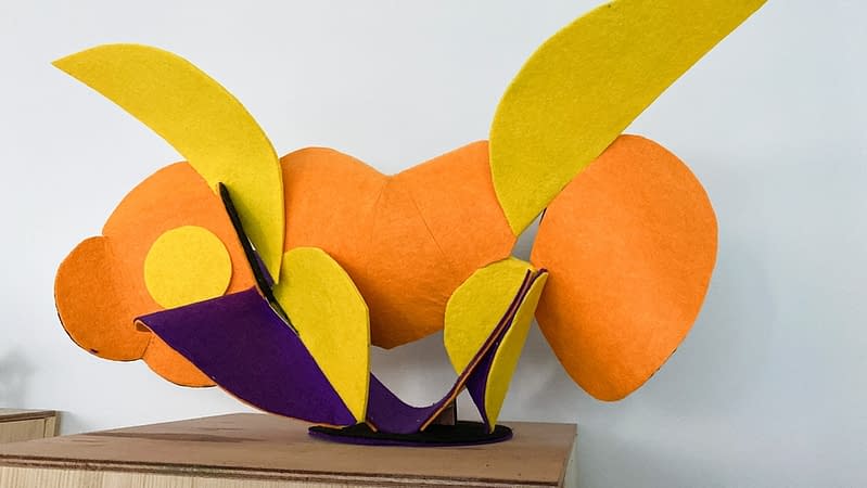 Back view of a sculpture made of thin bent layers with a soft felt finish in a mix of high saturated yellow, orange, purple and black colors. Artwork by Dado