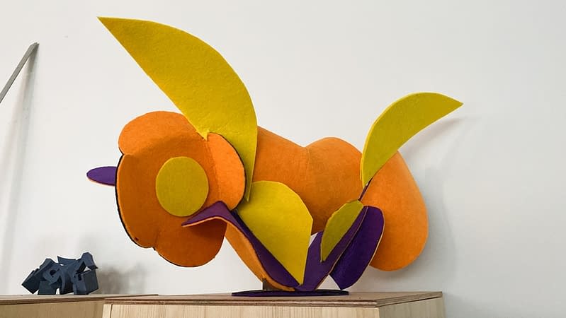 Low back view of a sculpture made of thin bent layers with a soft felt finish in a mix of high saturated yellow, orange, purple and black colors. Artwork by Dado